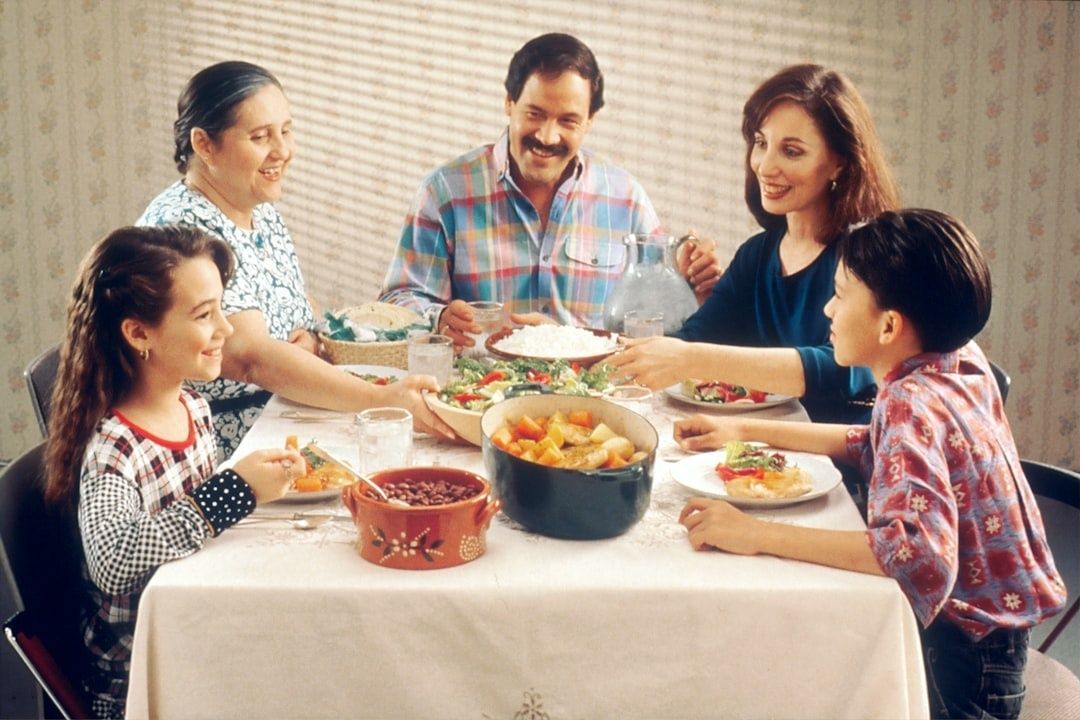 Mehrgenerationenfamilie sitzt gemeinsam an einem gedeckten Esstisch