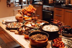Herbstliches Buffet mit Schmorgerichten, Gemüse, Brot und orangefarbenen Blumen